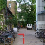 Nach den Fahrradständern befindet sich links eine weiße Tür.